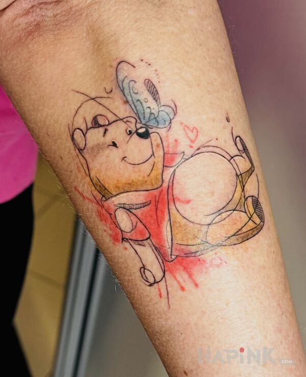Tattoo Winnie the Pooh in colorful motif and cartoon / comic book style on the forearm