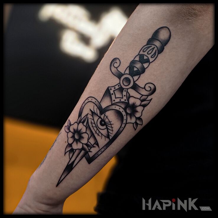 Tattoo Sztylet przebijający serce in flowers motif and oldschool style on the forearm