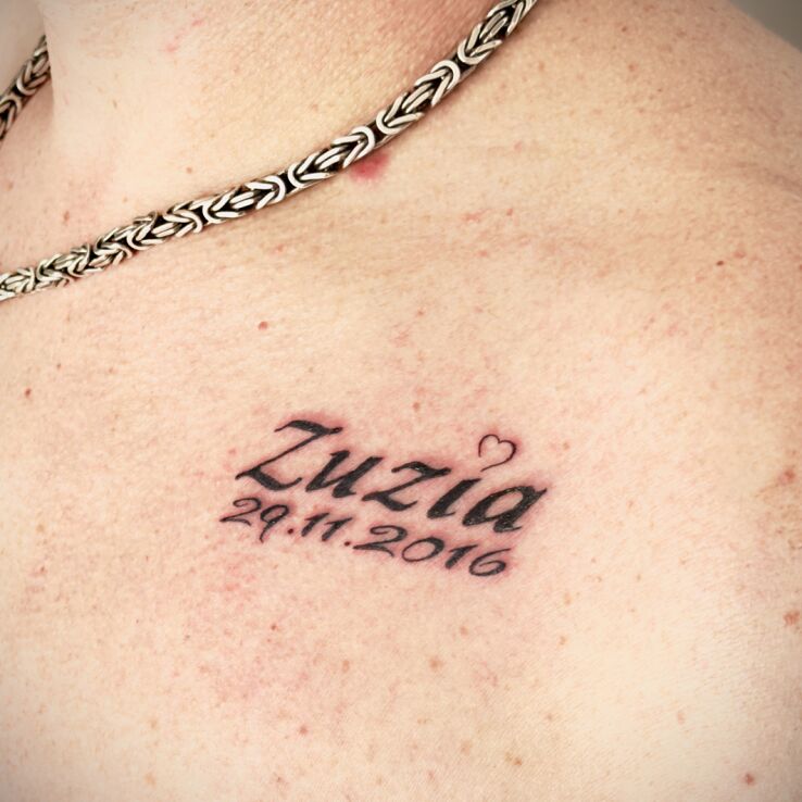 Tattoo Imię i data córki in lettering motif and calligraphy style on the chest