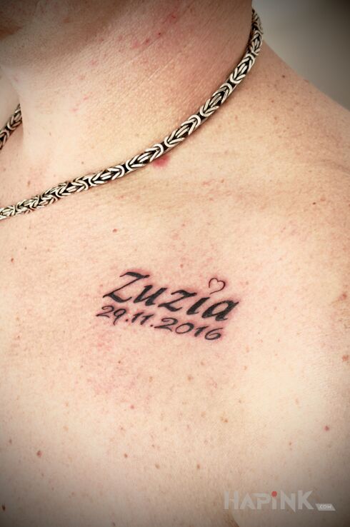 Tattoo Name and date of daughter in lettering motif and calligraphy style on the chest