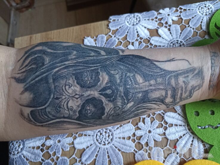 Tattoo Kower in faces motif and realistic style on the forearm