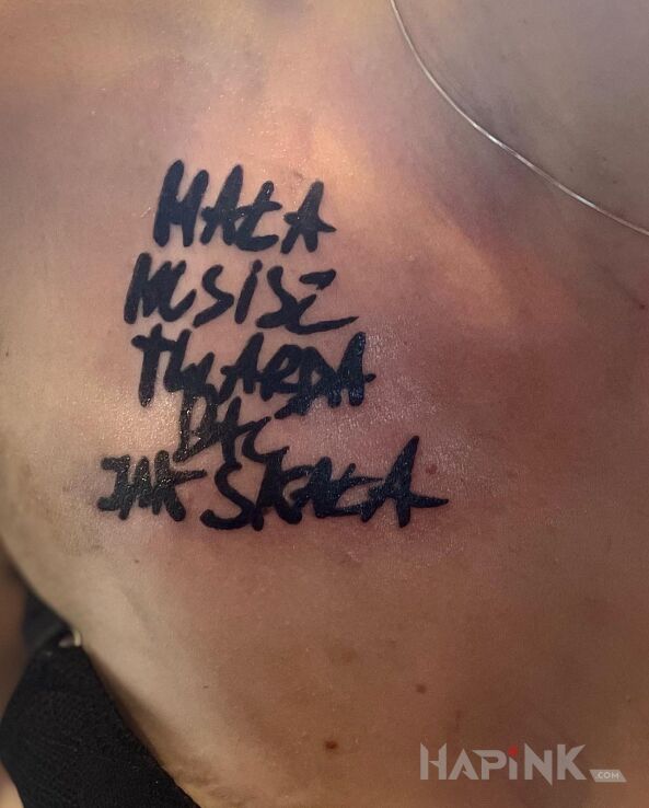 Tattoo Rapper's quote transferred from a piece of paper to the skin in black and gray motif and calligraphy style on the chest
