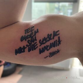 Tatuaż Własnoręczny cytat rapera przeniesiony na skóre na bicepsie motyw: napisy styl: kaligrafia