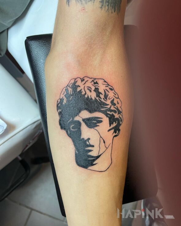 Tattoo Greek head in faces motif and graphic / illustrative style On the arm