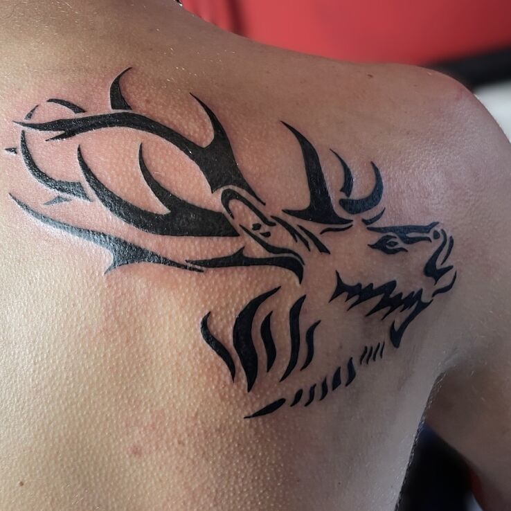 Tattoo Tribal jelen in black and gray motif and blackwork / blackout style on the back