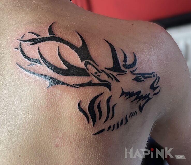 Tattoo Tribal deer in animals motif and blackwork / blackout style on the shoulder blades