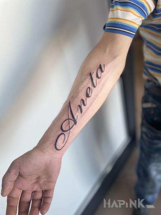 Tattoo Wife's name in lettering motif and calligraphy style on the forearm