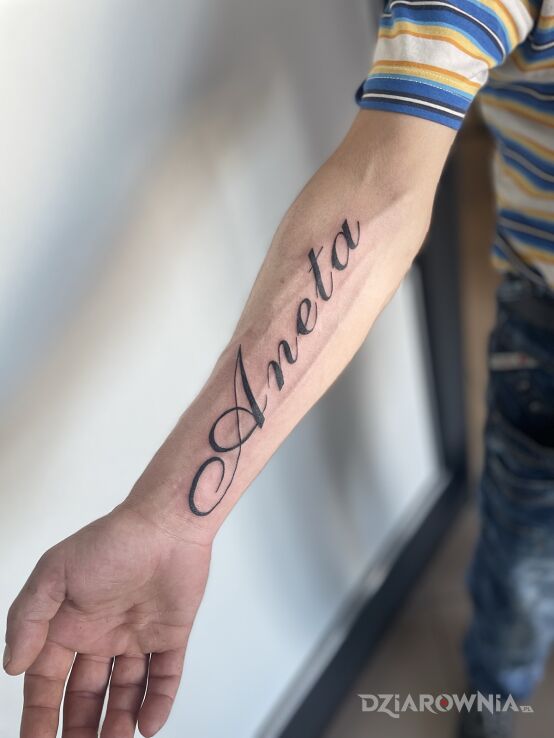Tattoo Imie żony in lettering motif and calligraphy style on the forearm