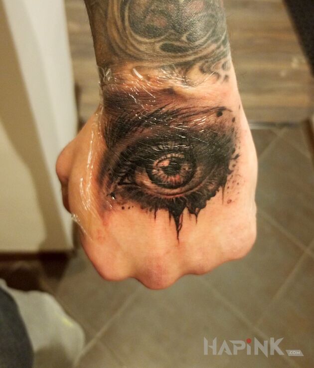 Tattoo Eye in black and gray motif and realistic style on the hand