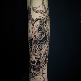 Tattoo Leszy with a human skull on the forearm motif: black and gray style: graphic / illustrative