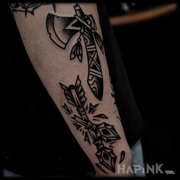 Tattoo Arrows and axe in Indian motif and oldschool style on the forearm
