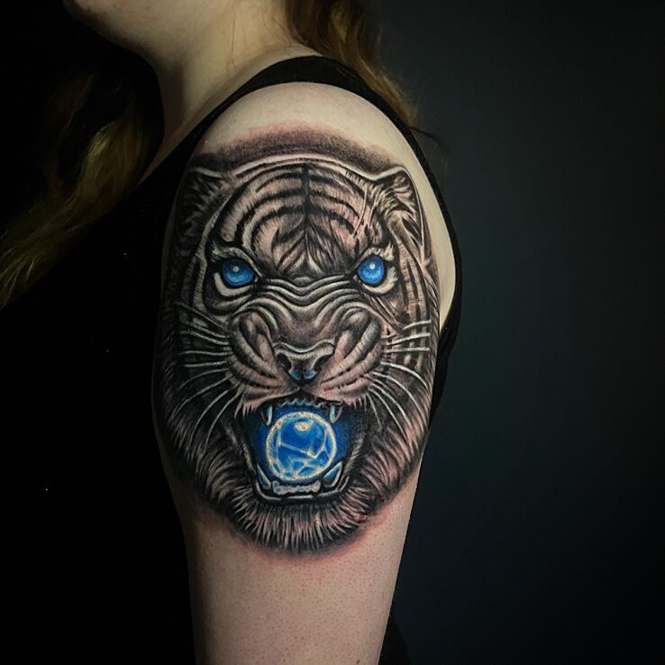 Tattoo Black and shaded tiger with blue elements in fantasy motif and realistic style on the shoulder