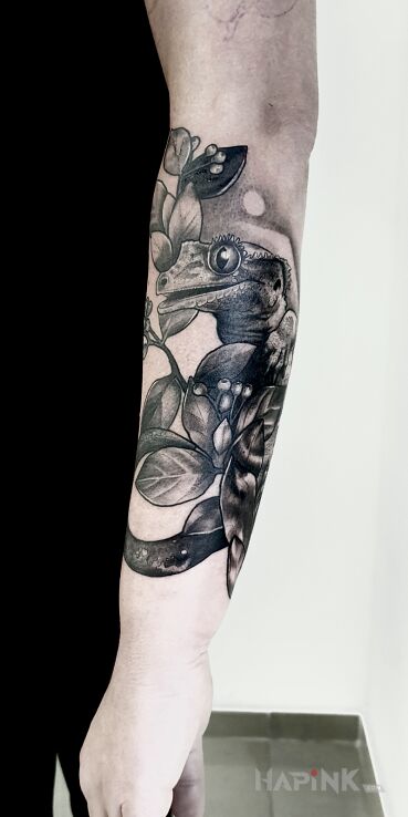 Tattoo Perched gecko in floral motif and realistic style On the arm