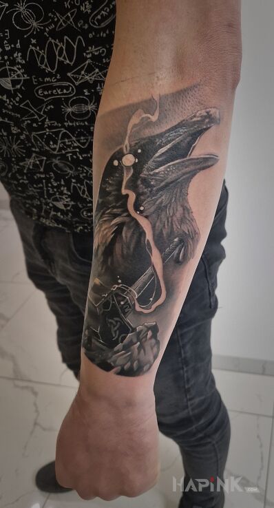 Tattoo Raven in black and gray motif and realistic style on the forearm