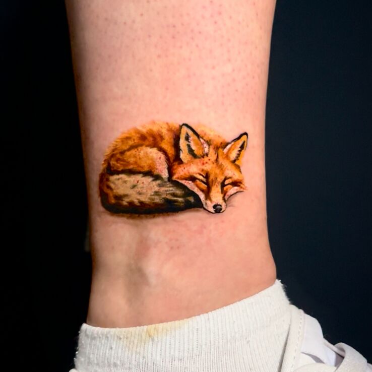Tattoo Colorful fox by the ankle in animals motif and realistic style on the leg