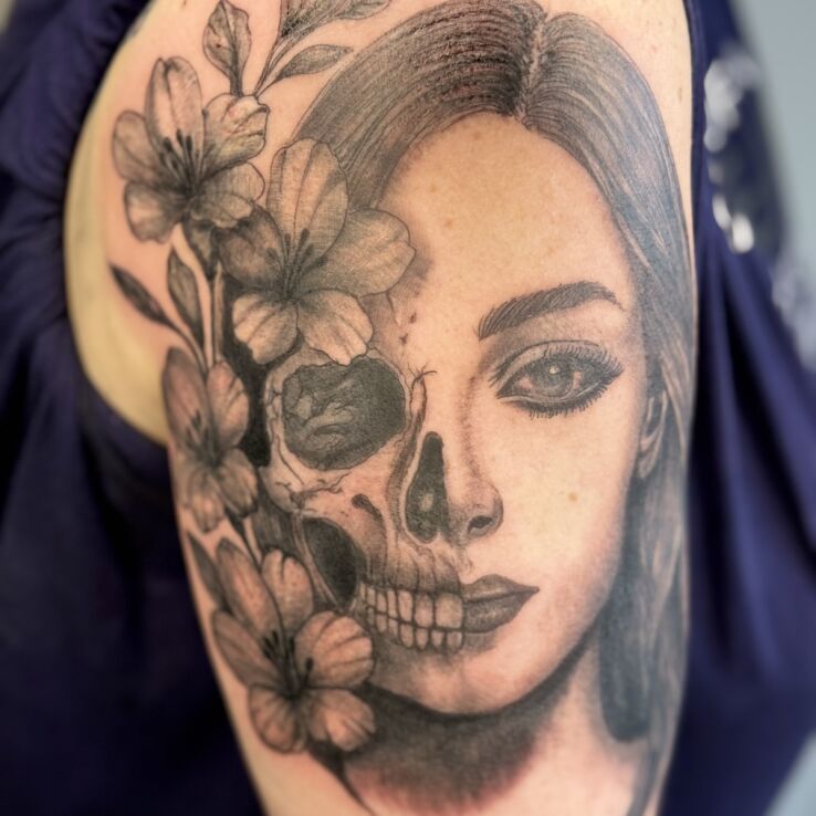 Tattoo "Life is a short moment." in flowers motif and realistic style on the upper arm