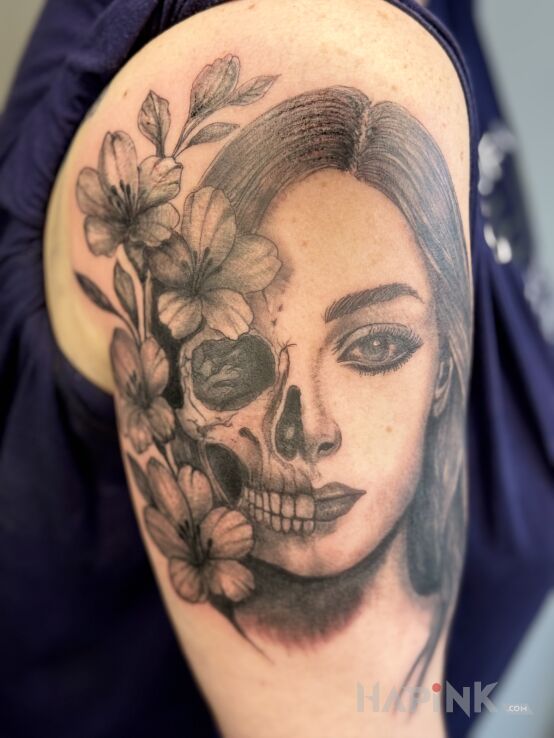 Tattoo "Life is a short moment." in skulls motif and realistic style on the upper arm