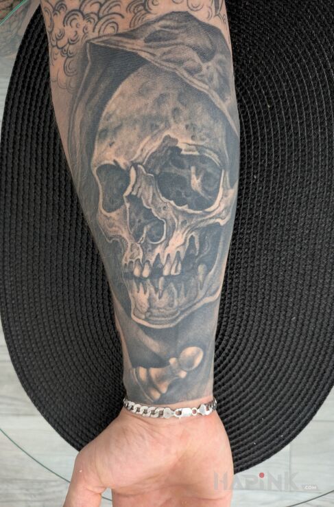 Tattoo Czacha w kapturze in dark motif and realistic style on the forearm