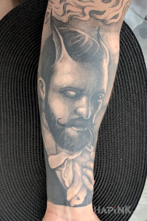 Tattoo Lucyfer buchający z drewnianej fajki in faces motif and realistic style On the arm