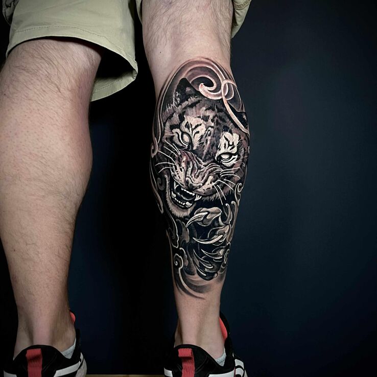 Tattoo Tygrys w ataku in black and gray motif and graphic / illustrative style on the calf