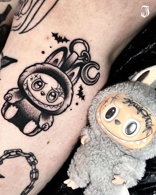 tatuaż labubu na nodze i figurka the monsters