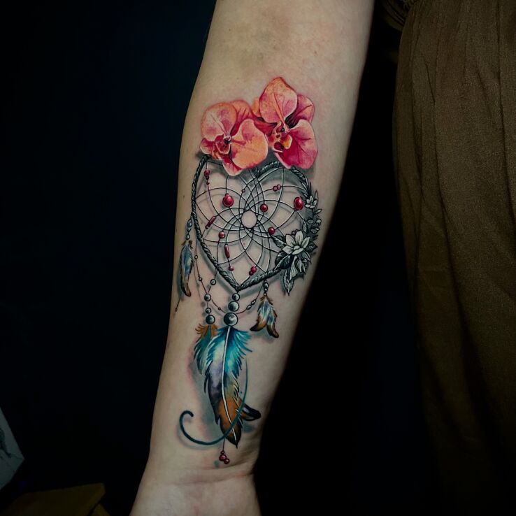 Tattoo Dreamcatcher with flowers and feathers in colorful motif and realistic style On the arm