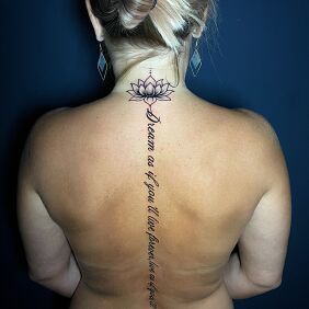 Tattoo Lotus flower with a straight inscription on the spine on the back motif: flowers style: graphic / illustrative