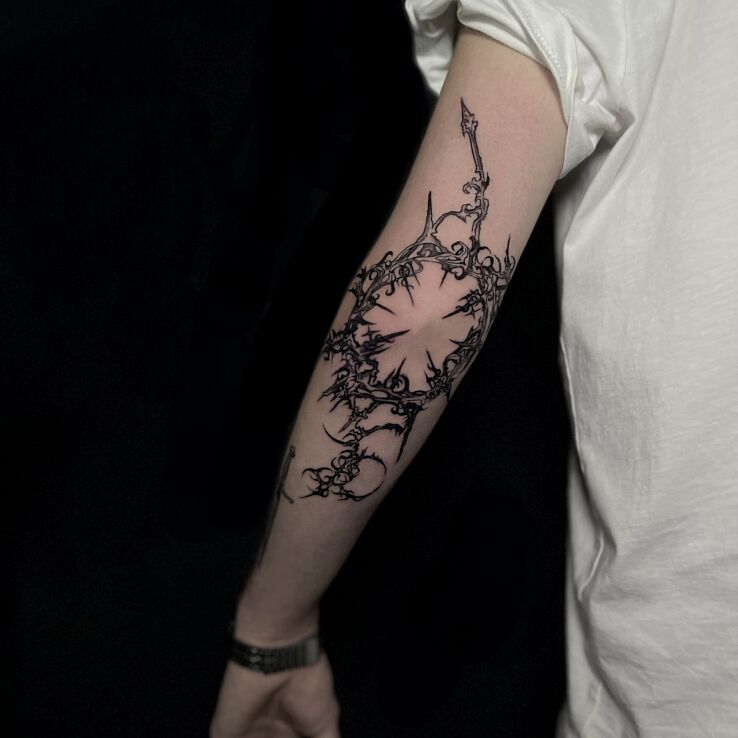 Tattoo Cybersigilism neotribal around the entire elbow in black and gray motif on the forearm