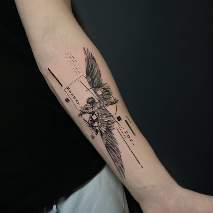 Tattoo Falling Icarus with Latin inscription in black and gray motif and graphic / illustrative style On the arm
