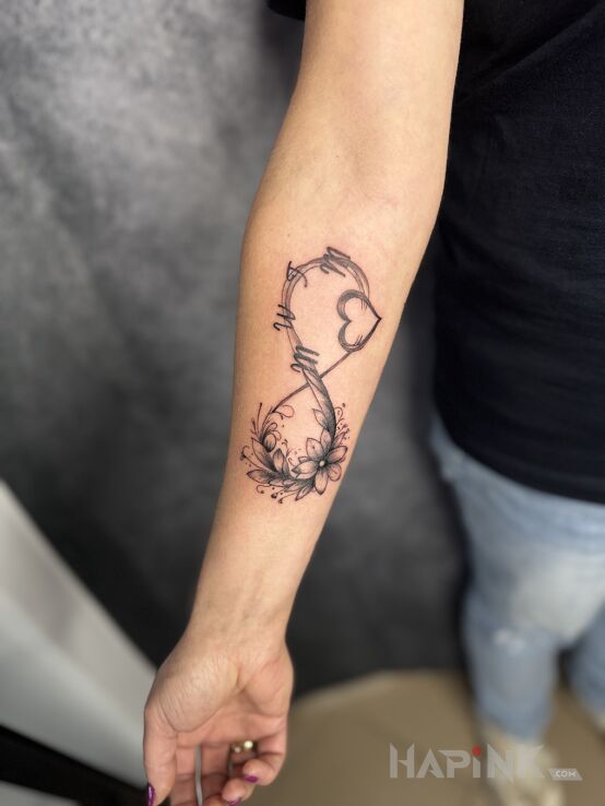 Tattoo Infinity symbol in flowers motif and graphic / illustrative style on the forearm