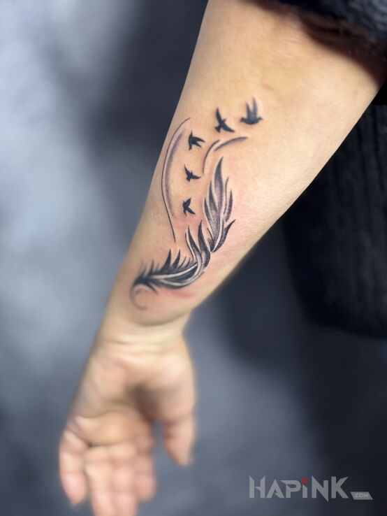 Tattoo Feather with birds in black and gray motif and graphic / illustrative style on the forearm