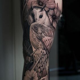 Tatuaż Sowa wśród kwiatów na udzie motyw: czarno-szare styl: dotwork