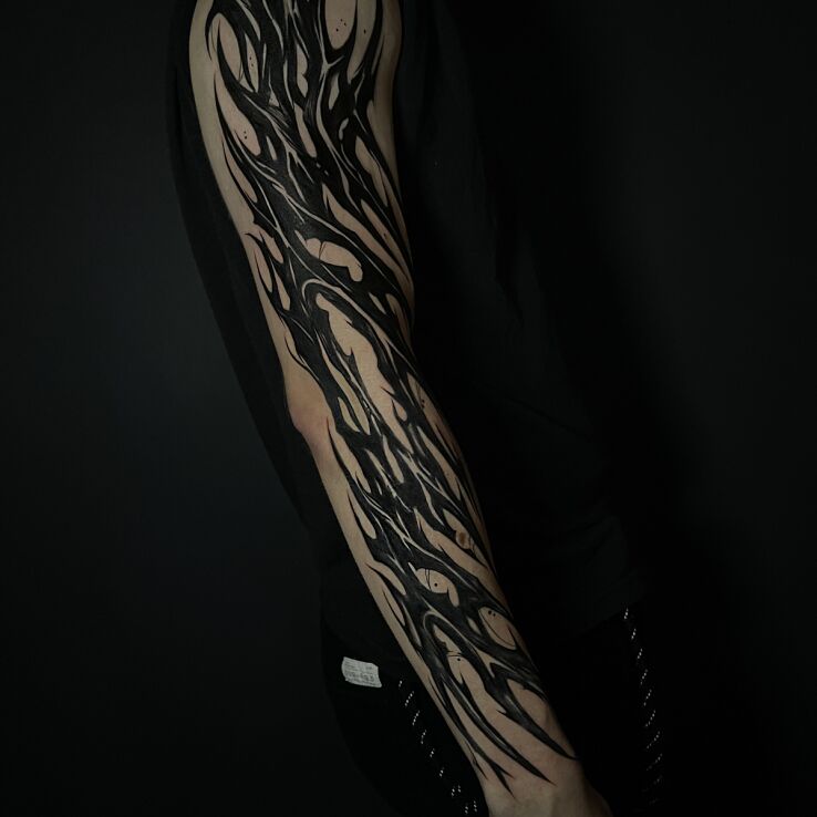 Tattoo Black neotribal full sleeve in dark motif and abstract style on the forearm