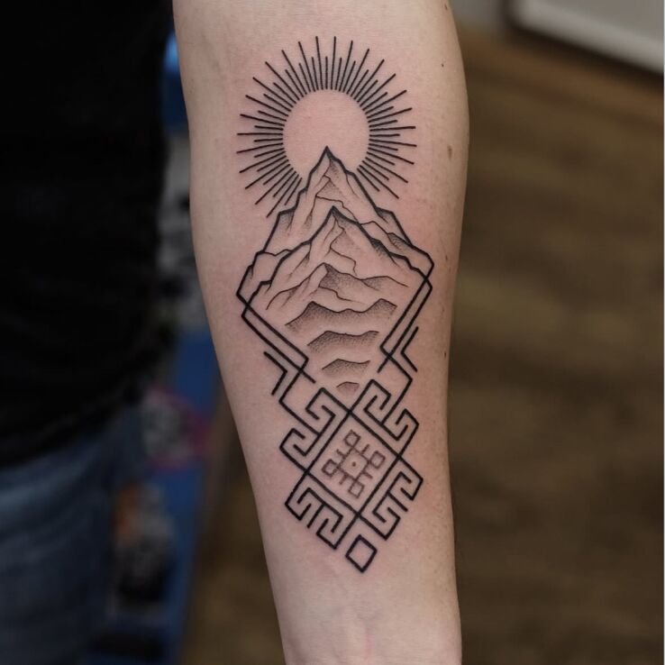 Tattoo Mountain and sun in a geometric frame in ornaments motif and contour / linework style On the arm