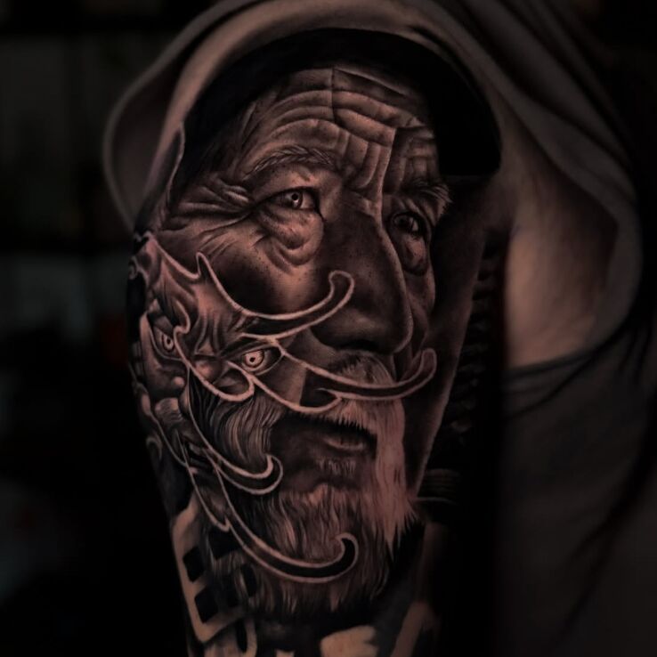 Tattoo Portrait of an Old Man in black and gray motif and realistic style on the upper arm