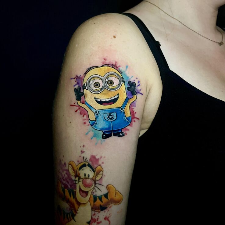 Tattoo Colorful and Smiling Minion in funny motif and Watercolor style on the upper arm