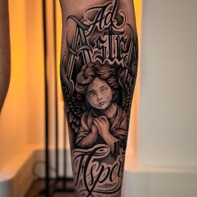 Tatuaż Ad Astra Aspera – Anioł i Chicano Lettering na nodze motyw: czarno-szare styl: chicano