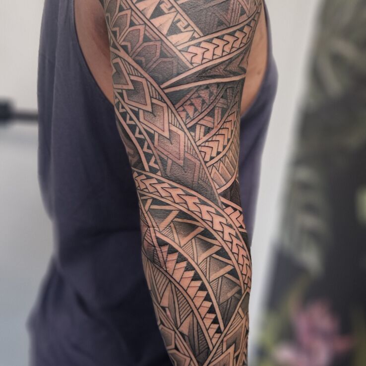 Tattoo Polynesian spearheads in a sleeve in sleeves motif and dotwork style on the bicep