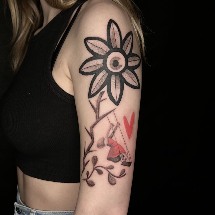 Tattoo Large Flower and Figure on a Swing in flowers motif and surrealistic style on the upper arm