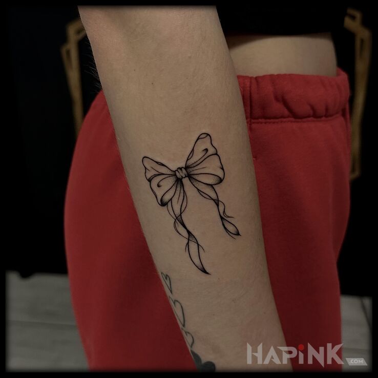 Tattoo Delicate Bow in black and gray motif and graphic / illustrative style on the forearm