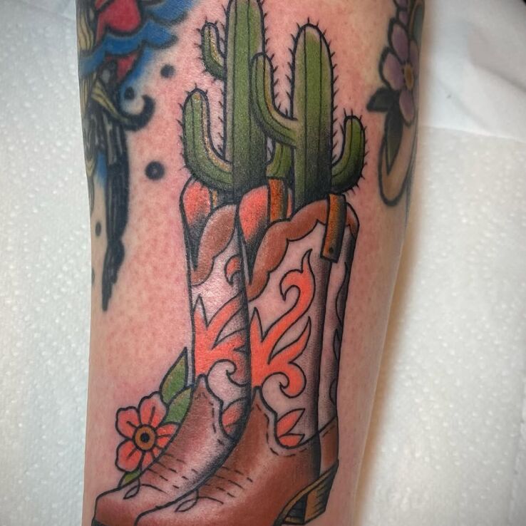 Tattoo Cowboy boots with cacti in floral motif and oldschool style on the tibia