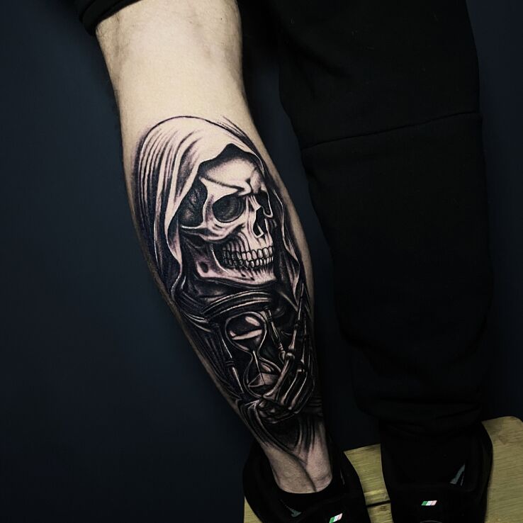 Tattoo Skeleton in a hood with an hourglass in dark motif and calligraphy style on the calf