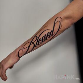 Tattoo Blessed Script On the arm motif: lettering style: calligraphy