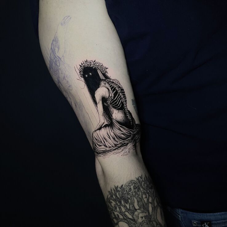 Tattoo Apparition in a wreath with exposed spine in dark motif and blackwork / blackout style on the upper arm