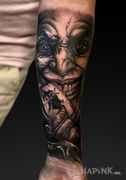 Tattoo Joker with a card in characters motif and realistic style on the forearm
