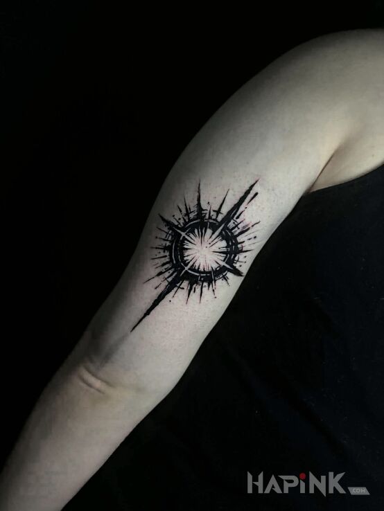 Tattoo Wheel with rays star in dark style in cosmos motif and blackwork / blackout style On the arm