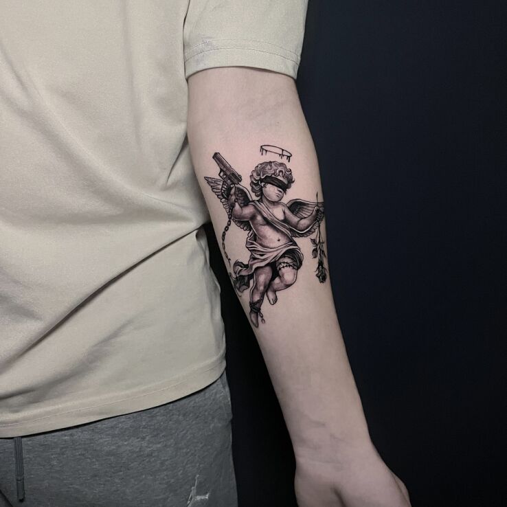Tattoo Little Angel with a Gun and a Rose in black and gray motif and graphic / illustrative style On the arm