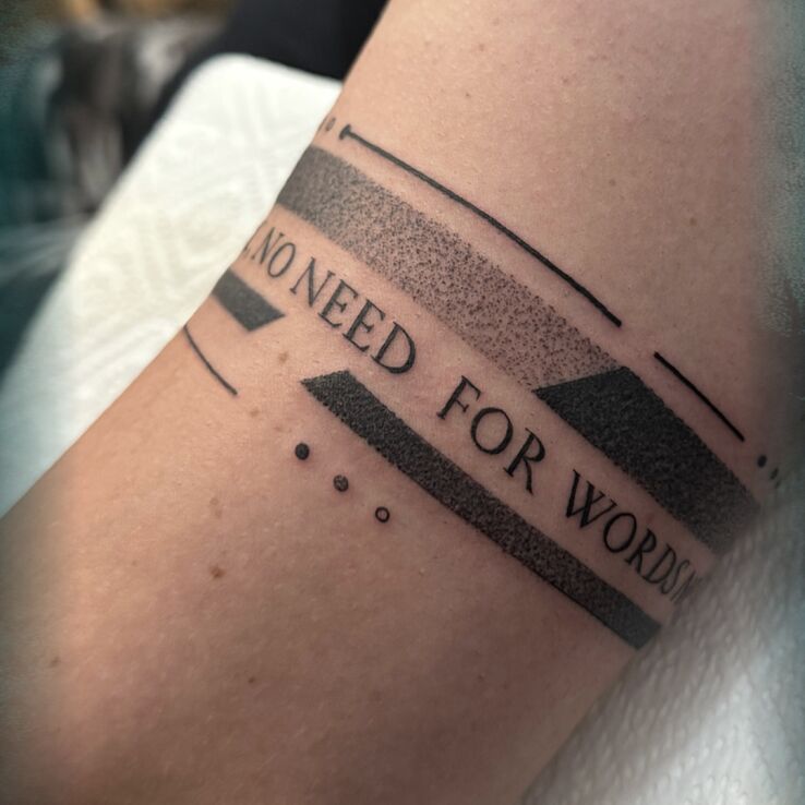 Tattoo 🔇 When Silence Speaks Louder Than a Scream 🔇 in lettering motif and dotwork style on the upper arm