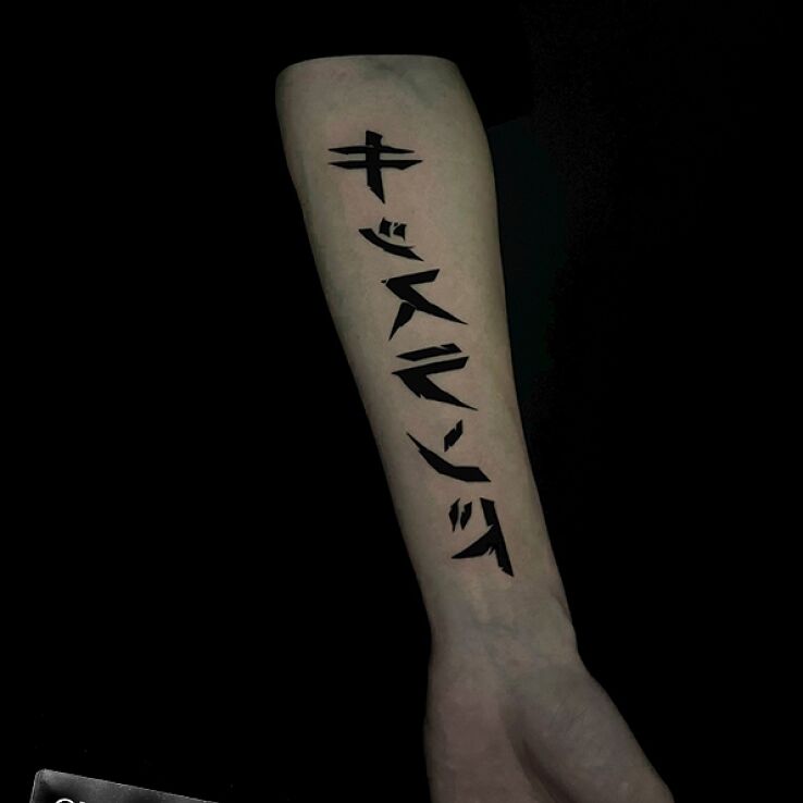 Tattoo Japanese characters in black and gray motif and blackwork / blackout style on the forearm