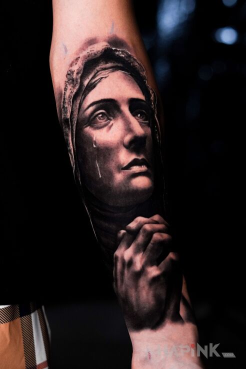 Tattoo Virgin Mary - Black and white tattoo. in religious motif and realistic style On the arm